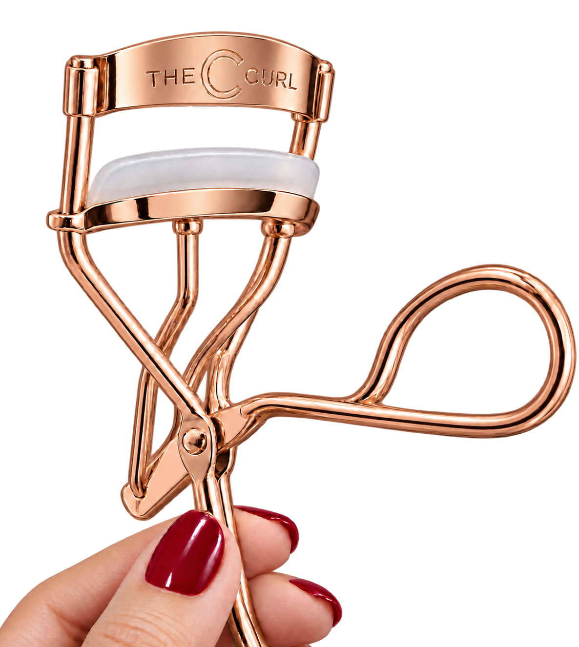 The rose-gold C Curl with its cushioned pad, held by a hand with deep red nail polish