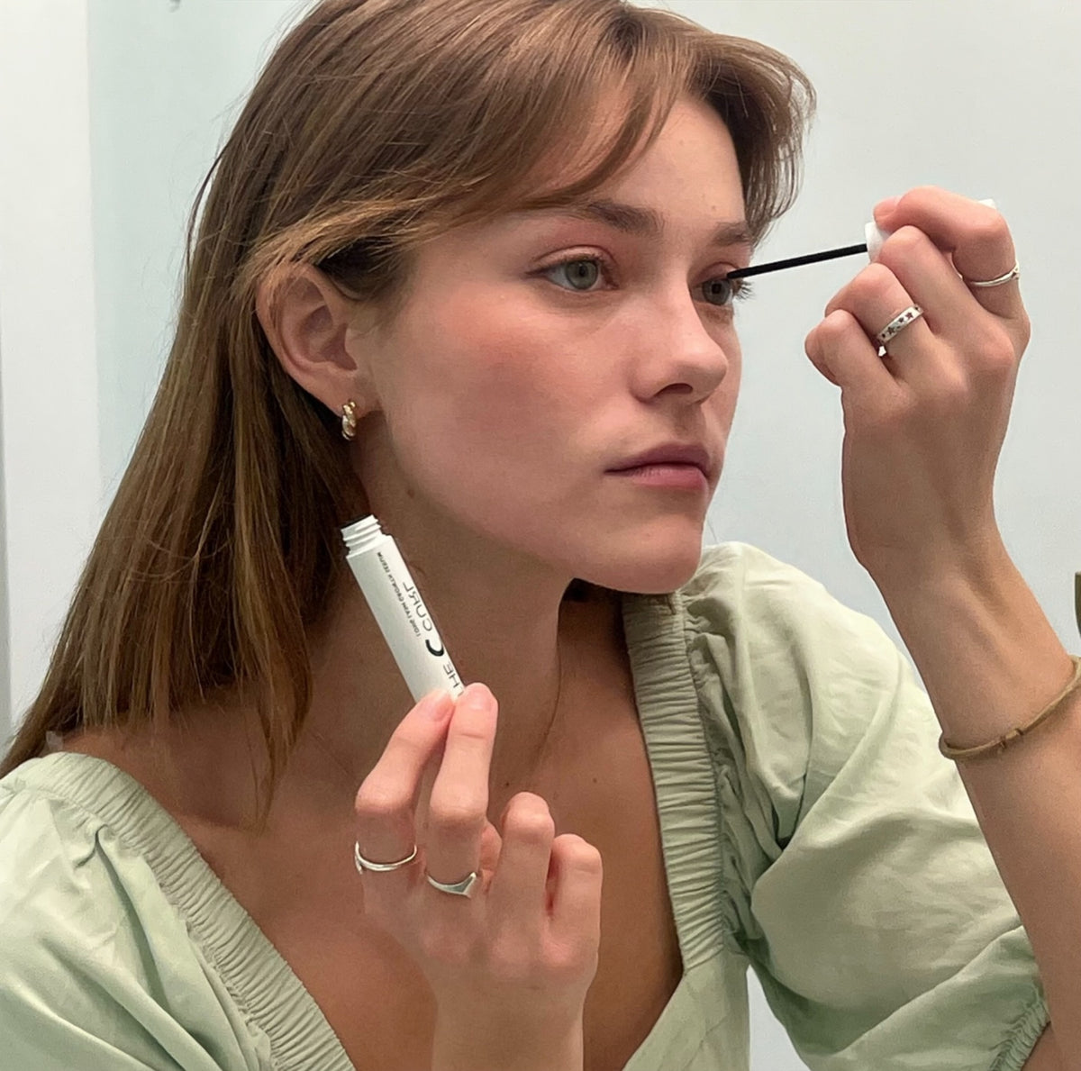 Woman applying Long Lash Growth Serum along her upper lash line