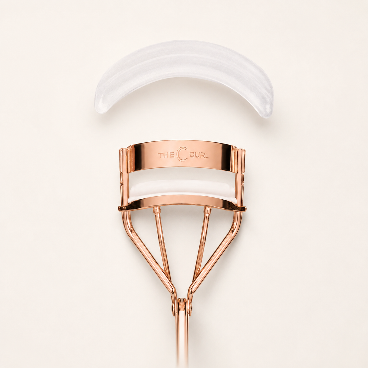 The curved translucent C Curl replacement pad shown above the rose-copper eyelash curler